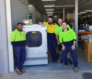 A group of men standing around the HUBSCRUB Machine